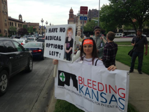 Photo by Andy Marso Christine Bay of Lenexa displayed a sign at the rally that included a photo of her daughter Autumn, who has a seizure disorder.