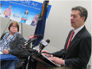 Photo by Dave Ranney Kansas Department for Children and Families Secretary Phyllis Gilmore looks on as Gov. Sam Brownback discusses a welfare reform measure that will take effect July 1. 