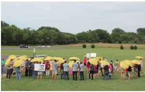 Participants in a June 23 rally  hold umbrellas to protest a proposal by Westar to make solar customers pay a higher monthly flat fee. photo by ANDY MARSO