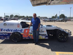 Former NASCAR driver Kenny Schrader stands next to his 1st class chassis IMCA modified race car at Schwan's Friday afternoon (Photo by Terry Tebrugge/Salina Post)