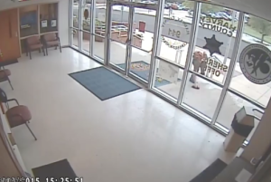 Suspect picks up a brick he just threw at the Law Enforcement Center.