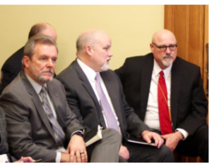 Yancey, right, talks with Aaron Dunkel, deputy secretary of KDHE, during a December 2015 legislative hearing on an audit of the Kansas Eligibility Enforcement System used to process Medicaid applications. At left is Mike Randol, director of the Division of Health Care Finance. The audit found that the KEES rollout was delayed because the software required numerous modifications. CREDIT FILE PHOTO