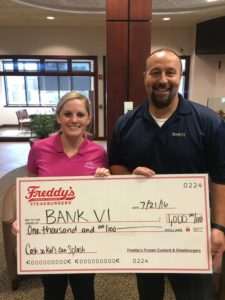 BANK VI Senior Vice President Chris Baker is presented with a check for $1,000 by Julia Zuppan of JRI Management.
