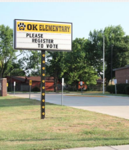 Photo by Abigail Wilson/KMUW While many educators are spending the summer on the campaign trail, the sign outside a public elementary school in Wichita urges voters to register.