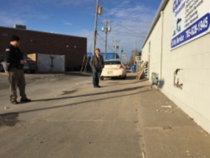 An officer from the Hays Police Department take pictures of the damage Monday morning while Clean Rite manager Chris Chesner looks on.