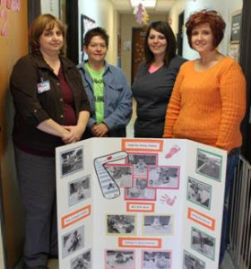 Shown (left to right) are: Marie Malo, Learn & Grow Depot Director; Mary Cairns, Lead Toddler 2 Teacher; Brandy Staggs, Lead Toddler 1 Teacher; Debb Homman, Infant/Toddler Specialist with Child Care Aware of Kansas. The group is pictured with an informational board showing some of the healthy practices the center is incorporating.