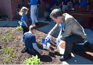 Gov. Brownback and a Christ the King Early Education Center student plant pinwheels .