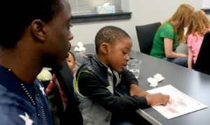 Salina Tech graduate Antoine Brathwaite watches his son read his certificate